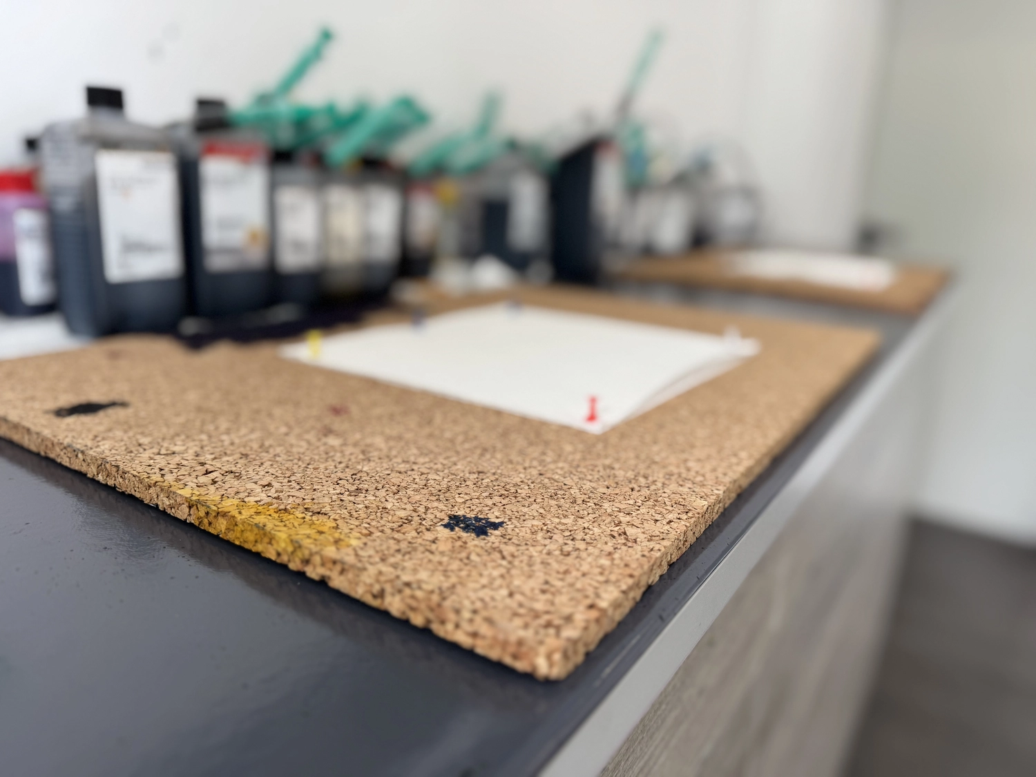 Mobile-color-Mobilfunkladen – eine Korkplatte oder -tafel, die als schützende Arbeitsfläche in einer Druck- oder Kunstwerkstatt verwendet wird.